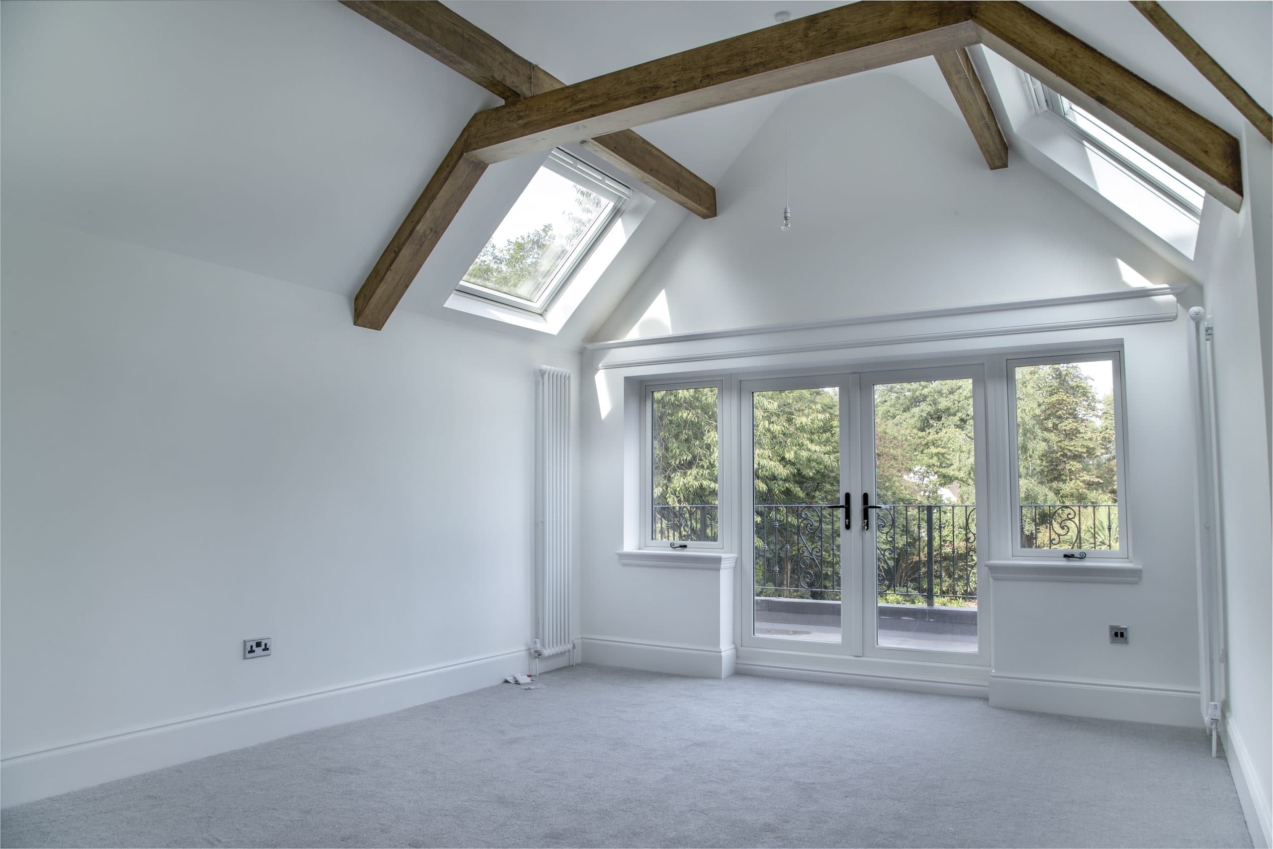 Empty room with wooden beams and a grey carpet